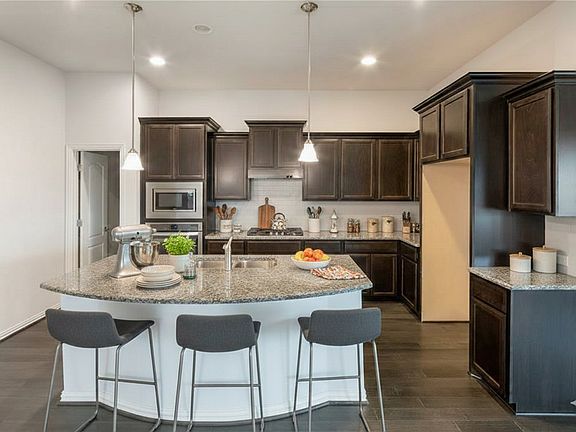 Kitchen with a large island, granite countertops, and stainless steel appliances - staged