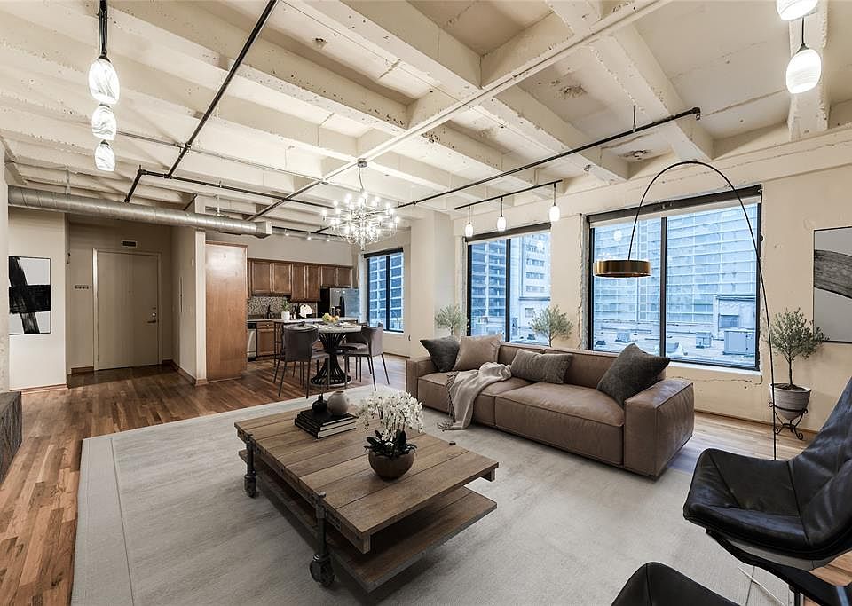 Virtually staged shot of the main living areas of Unit 602. Notice the open living, large windows, beautiful wood floors, pendant lighting, exposed ceilings - this is a must see!