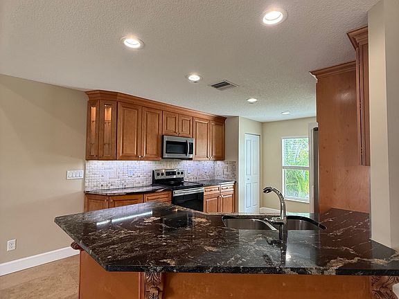 Granite counters thru out, note the tumbled marble back splash, accent lighting, corner wood cabinet and crown molding.