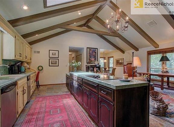 Vaulted ceilings w/ wood beams and skylights adorn this Kitchen/Hearth Room area.