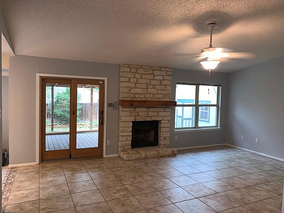 Fireplace, ceramic floors and windows in vaulted living area..