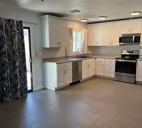 Dining Room view to Kitchen, Cabinets, Appliances, Ceiling Fan with Light, Tile and Grout Flooring, Baseboard Molding, Brand New Keyed Lock Sliding Glass Patio Door, Curtains.