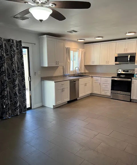 Dining Room view to Kitchen, Cabinets, Appliances, Ceiling Fan with Light, Tile and Grout Flooring, Baseboard Molding, Brand New Keyed Lock Sliding Glass Patio Door, Curtains.