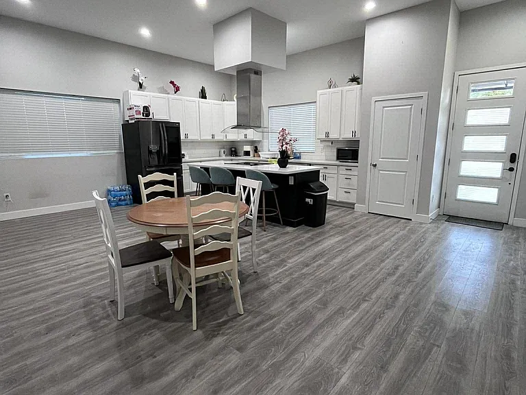Open kitchen with island seating, stainless appliances, and ample white cabinetry, flowing into an eat-in dining area.