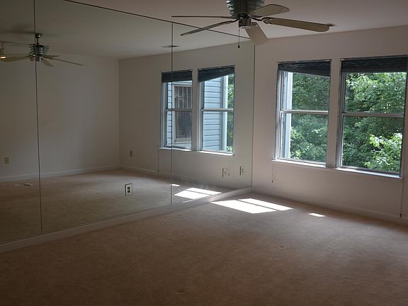 Master bedroom with walk-in closet, attached bathroom, mirrors and a ceiling fan