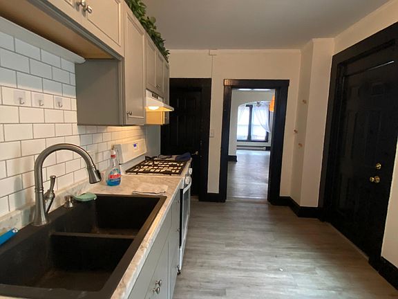 Modern Kitchen with upgraded lights, a 1/2 bathroom, double sink, tile backsplash, and access to side brick porch