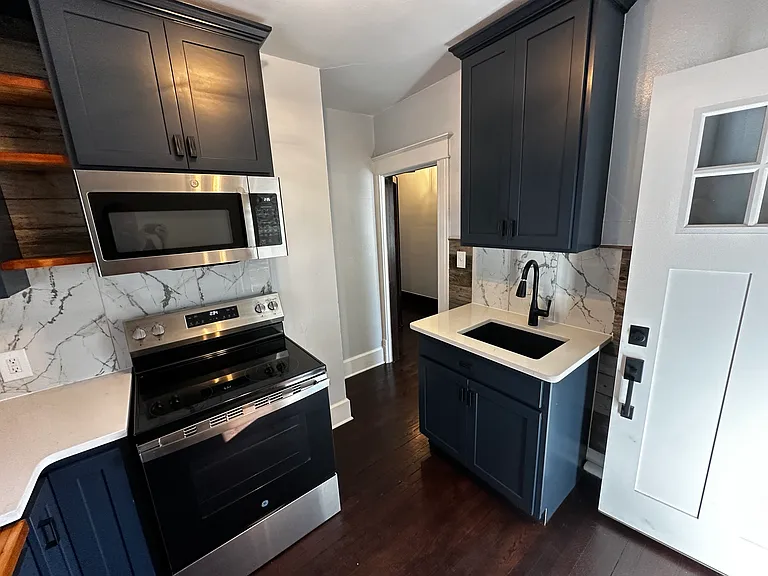 Custom shaker cabinets in powder blue. Stainless steel appliance pkg. Marble back splash, quartz counter/sink tops. Nick-knack open shelves