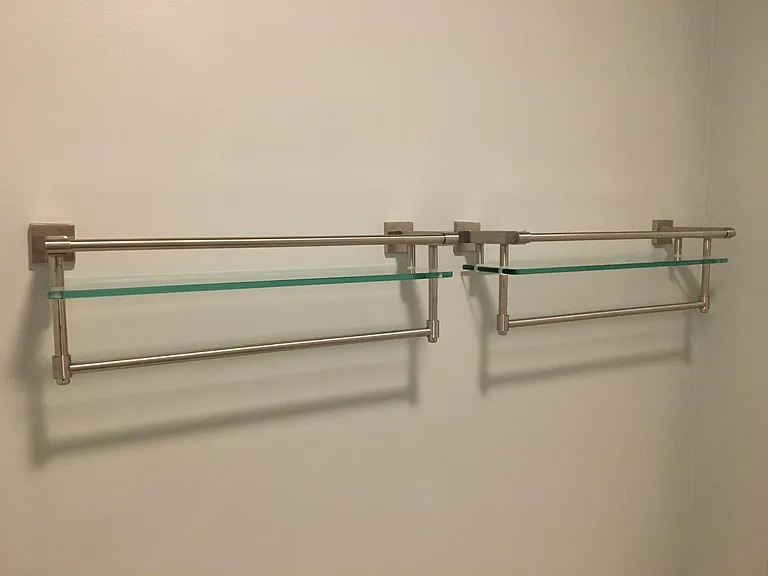 Three shelves in the bathroom with their own towel bar to help organize your bathroom items