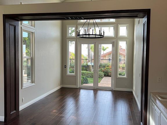 View into formal dining room from front door entry. Wet bar in formal living room, custom wood trim and light fixture