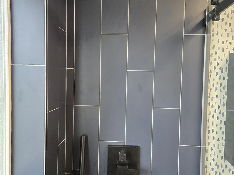 Kohler large rain head and hand held wand. Wall to wall shower doors.