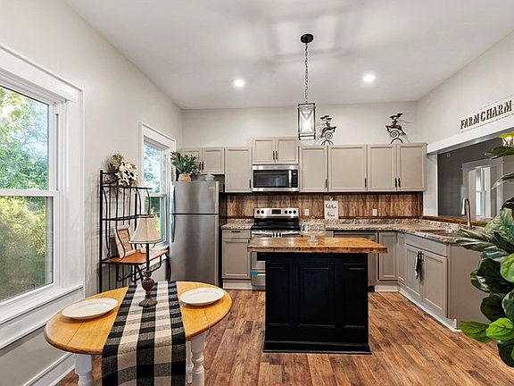 Stainless steel appliances and black island with butcher block.