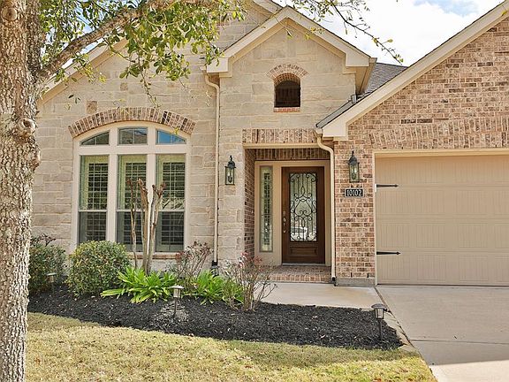 Terrific curb appeal with understated stone and brick accents, a brick enclosed covered doorway with pretty three quarter light wrought iron and stained wood door with shutters on the sidelight.