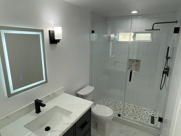 Fully updated bathroom featuring a walk-in glass shower, custom tile work, LED mirror, and modern vanity.