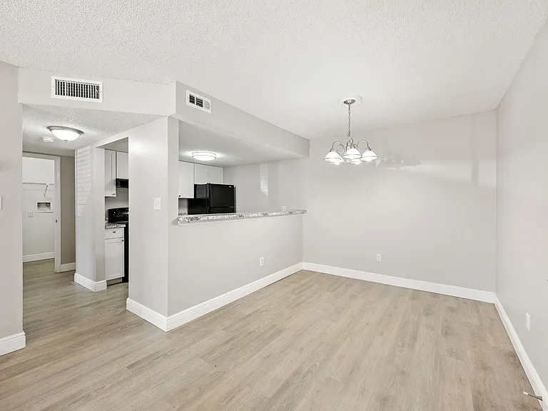Modern open-plan space featuring a cozy dining area with elegant lighting and a sleek kitchen with black appliances.