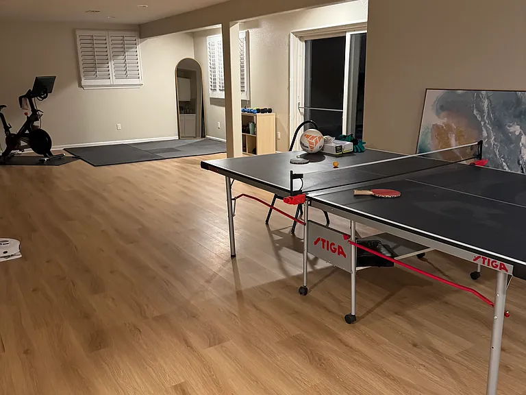 Peleton and ping pong table in basement living area