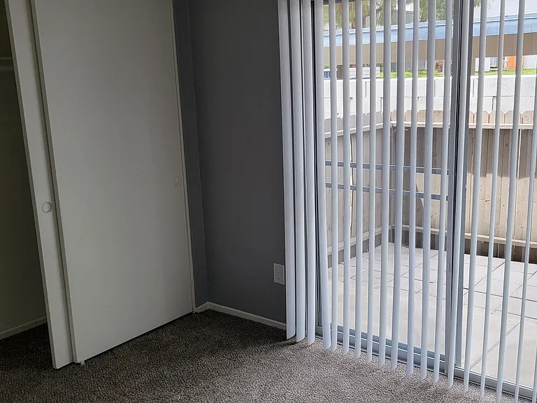 Carpeted bedroom with private porch at Grand Oaks Apartments in Lake Elsinore, California.