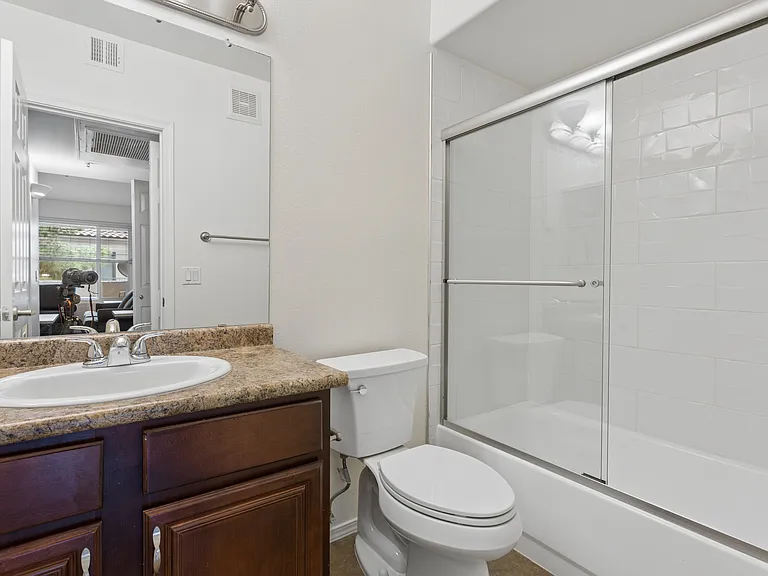 Guest bath shows glass shower doors, pretty white tile and large vanity mirror