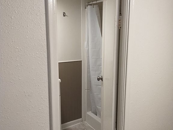 Small shower and storage shelves in bathroom which is located in the bedroom.