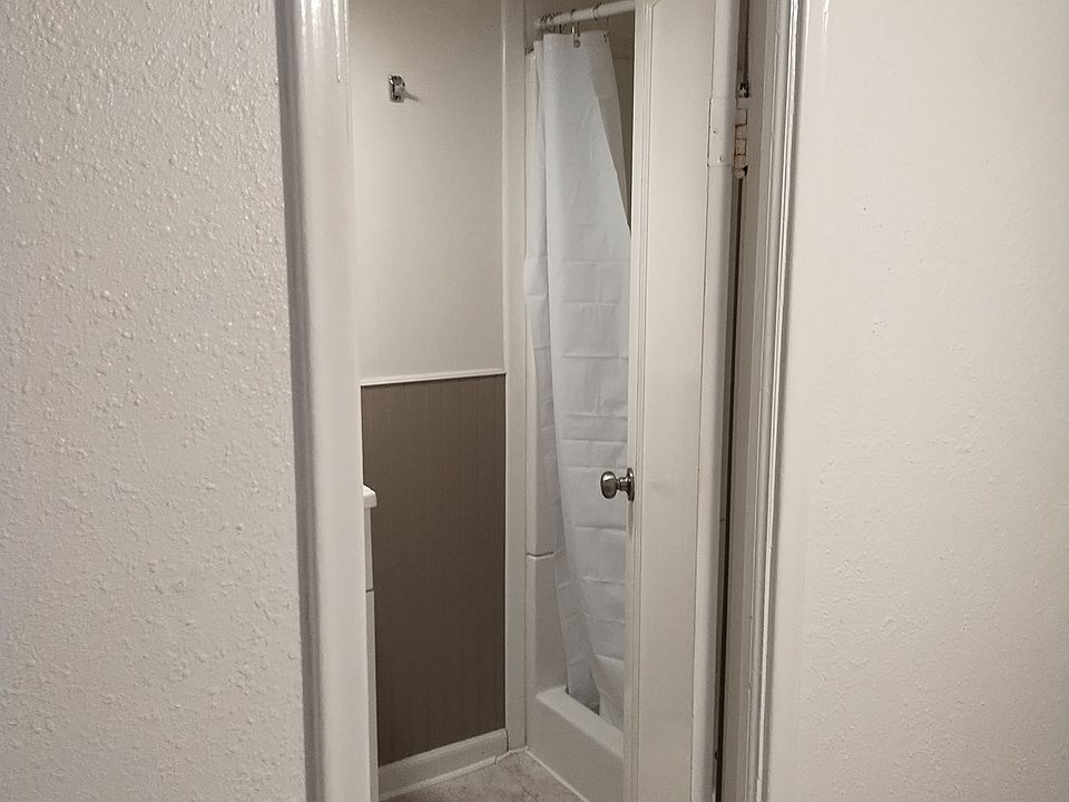 Small shower and storage shelves in bathroom which is located in the bedroom.
