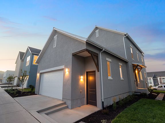 Modern two-story gray house from the Contempo Collection with a white garage door, lit porch lights,