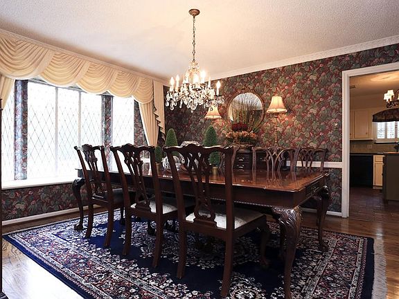 Very spacious formal dining room with designer wallpaper, hardwood floors, crown moldings, chandelier and lovely leaded glass bay window.