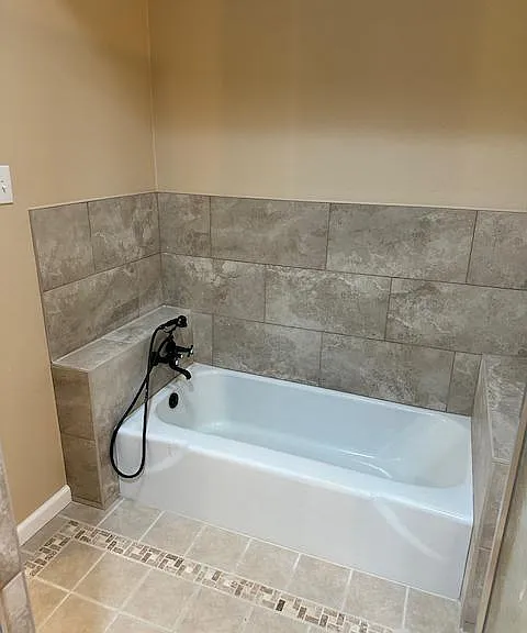Master suite bathtub features new tile surround and fixture.