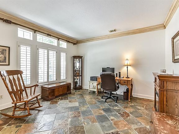 The formal living features slate tile floors and crown molding above. This room is currently being used as an office.