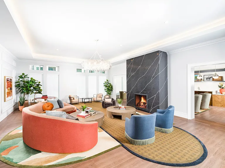 Spacious community lounge with a statement fireplace, curved seating, and soft lighting creating a welcoming space for gathering and relaxed conversation.