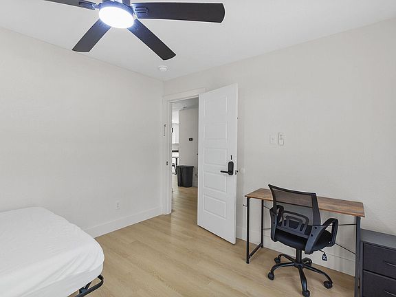 Private bedroom with a ceiling fan, wood-style flooring, and a dedicated desk area for work or study.