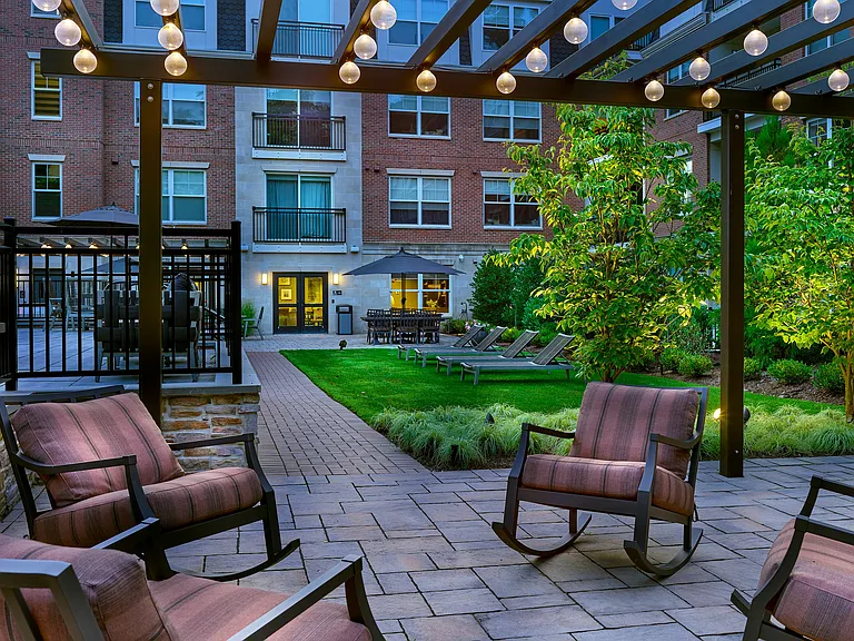 Experience our charming outdoor courtyard with modern seating, lush greenery, and ambient lighting, perfect for relaxation.