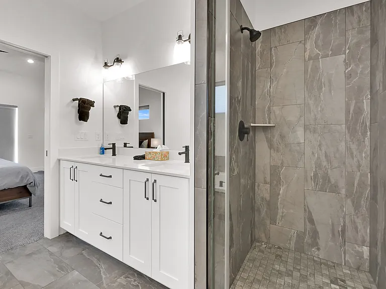 Master bathroom with his and hers sinks, walk in shower, large bathtub, and separate toilet room