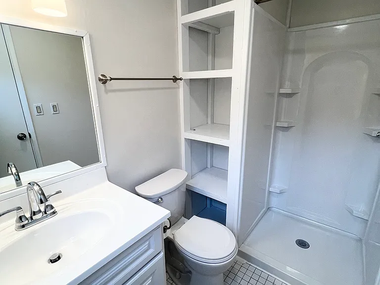 Master bathroom featuring built in storage, new vanity & fixtures, shower, and oversize mirror.