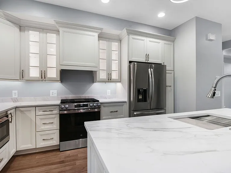 kitchen view showing undercounter microwave, gas stove and oven, vented hood ducted outside, pull out pantry beside fridge, lighted 42 inch cabinets, 10 foot ceiling height throughout.