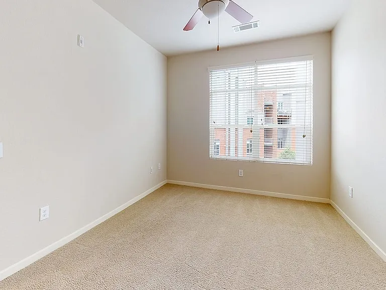 Spacious apartment bedroom with plush carpet flooring.