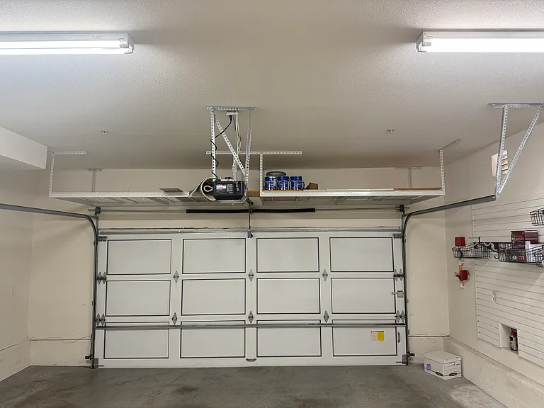 Attached 2-car garage features organized shelving.
