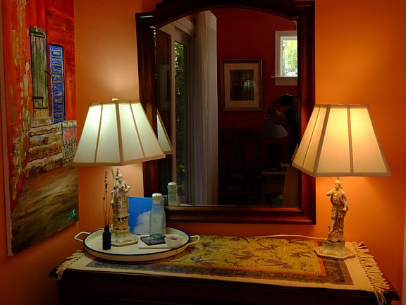 Antique dresser aside the king bed with antique lamps. Original oil painting completes the ensemble.