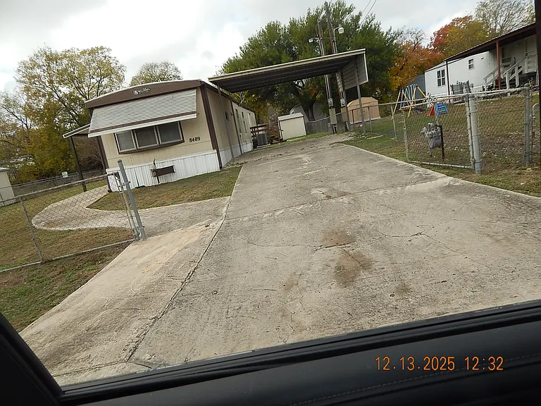 Front of home showing large driveway with 2 vehicle carport & storage shed at rear of home.