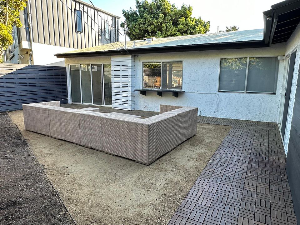 The generous backyard offers ample room for lounging, highlighted by a built-in bar window, sliding glass door access from both the dining room and primary bedroom, and a modern slatted privacy fence.