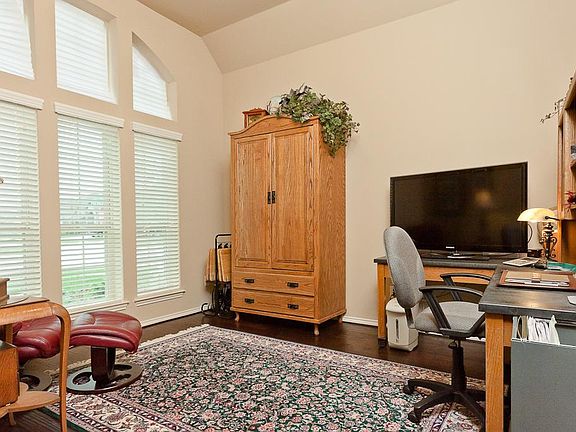 French doors off entry lead to study with wood floors and floor to ceiling windows.