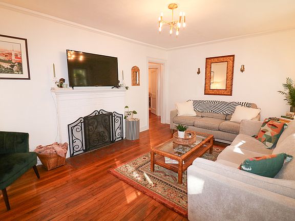 Main living room with two large couches, a 50 inch smart tv, original hardwood floors. Opens to front screened in porch for natural light.