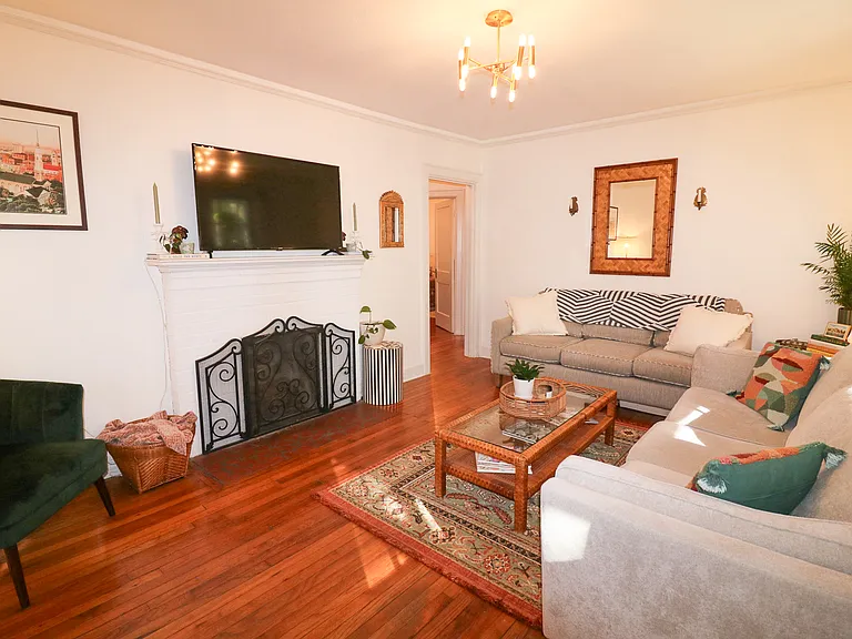 Main living room with two large couches, a 50 inch smart tv, original hardwood floors. Opens to front screened in porch for natural light.