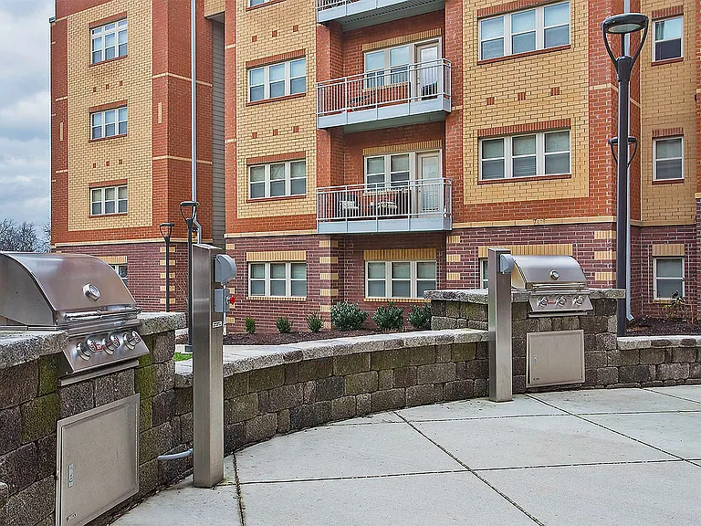 Relax and entertain in this chic outdoor grill area set against a modern apartment backdrop.