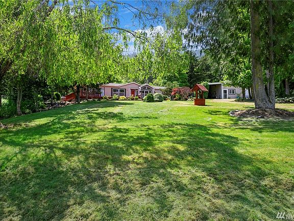 A beautiful view of the charming home, nestled among the trees with a seasonal creek running alongside, and a spacious detached carport and bonus area.