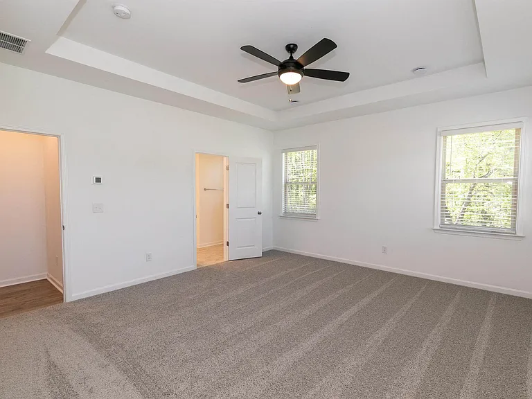 Secondary suite with plush carpet and windows for natural lighting.