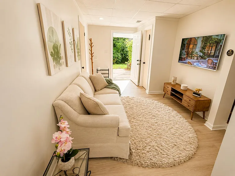 Compact living area with a sectional sofa, wall-mounted TV, and direct access to the patio and yard.