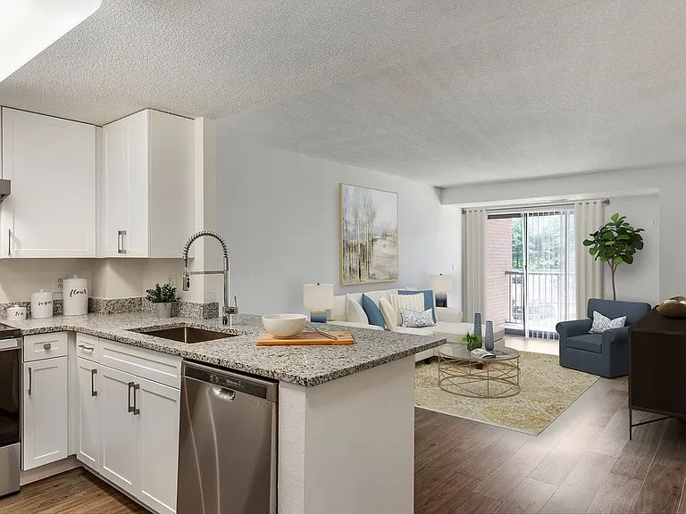 Renovated Package II kitchen and living area with white cabinetry, quartz countertops, stainless steel appliances, and hard surface flooring