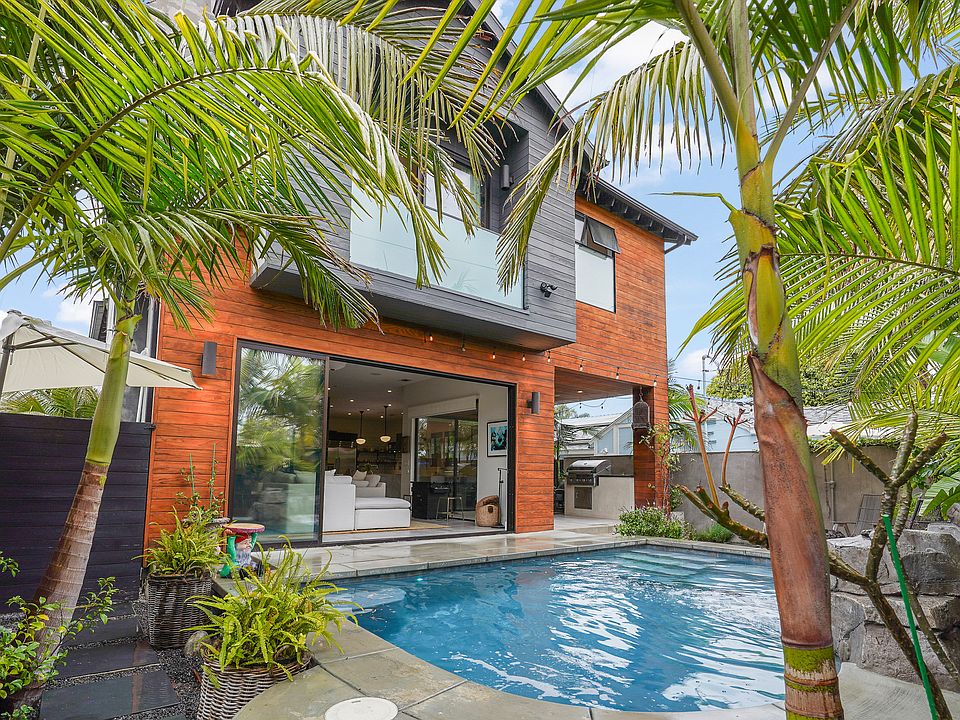 View of the living room from the verdant backyard oasis with heated pool, firepit and patio
