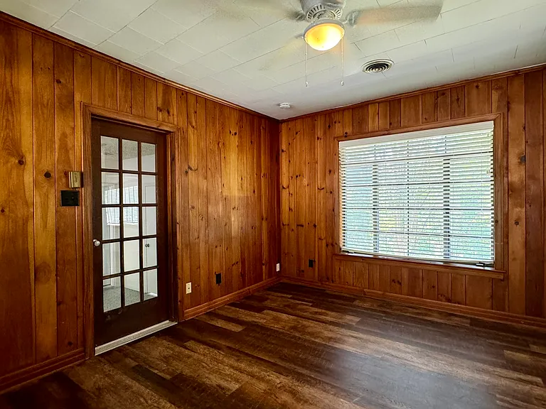 Den with original wood plank walls and new laminate flooring; door to Bedroom 3 to the left.
