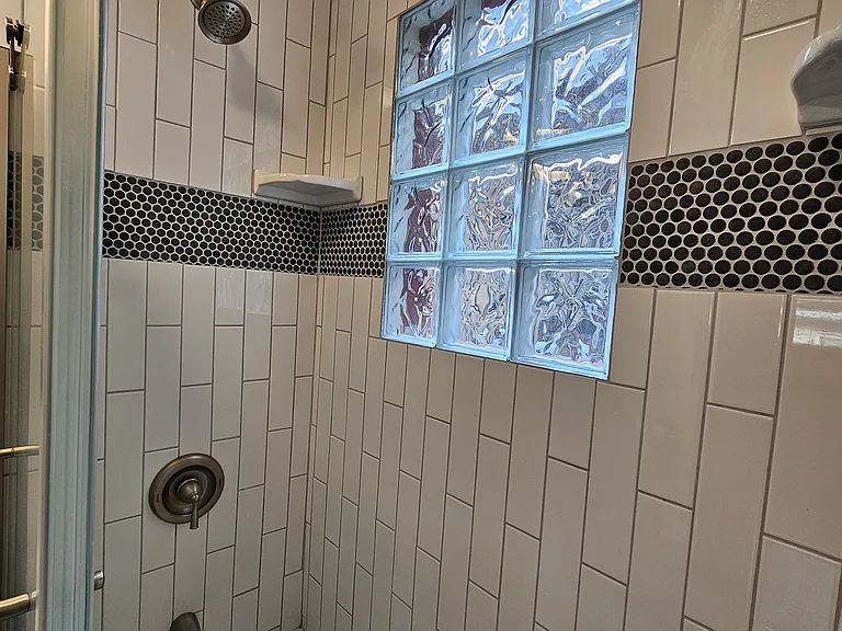 Shower has exhaust fan and glass block windows for natural lighting and privacy.