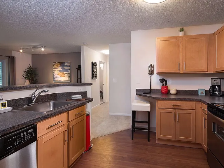 Classic Package kitchen with stainless steel appliances, black speckled laminate countertops, maple cabinetry and hard surface flooring